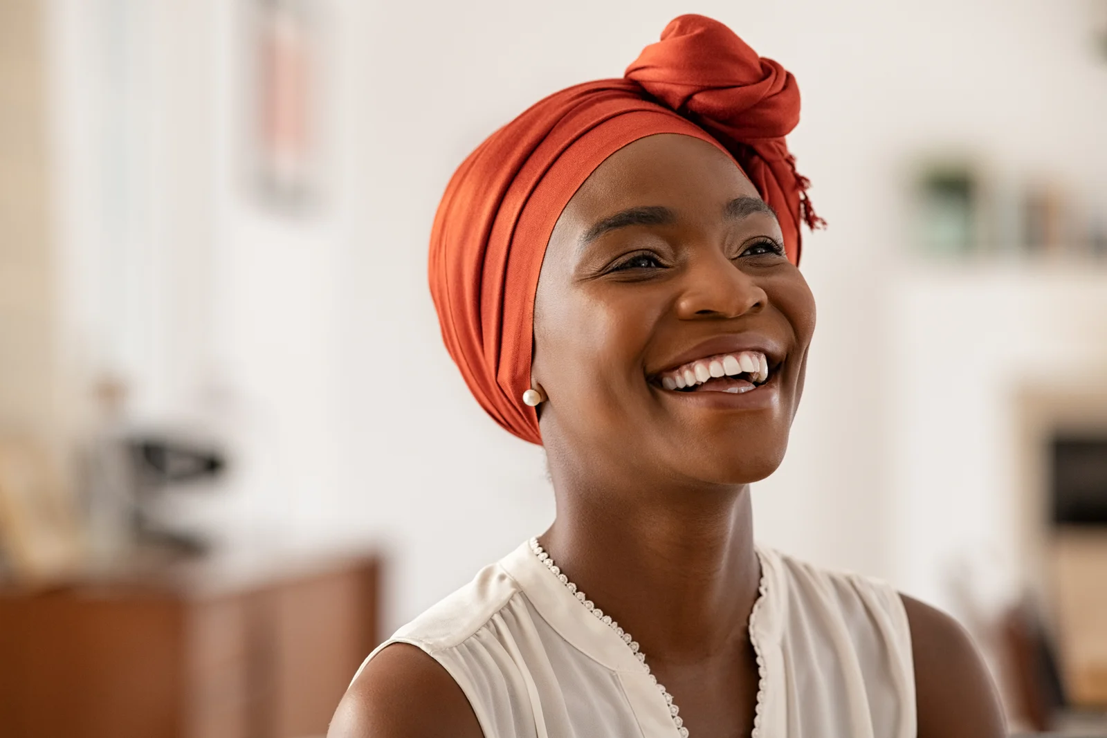 A smiling woman wearing an orange headwrap