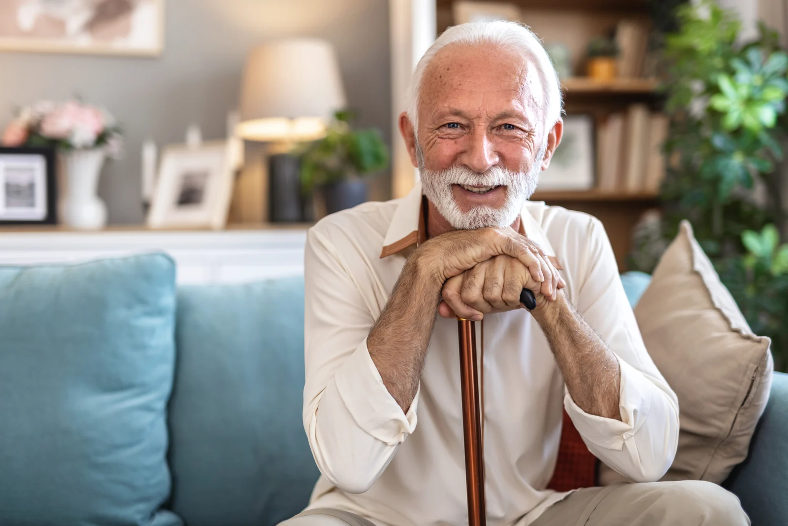 A smiling older man resting his hands on a walking cane
